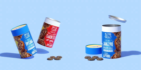 Three cylindrical containers of cookies with open lids and cookies scattered around on a blue background.