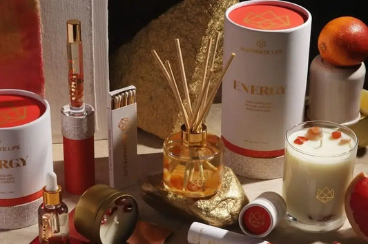 A collection of luxury lipstick packaging in elegant red and gold, displayed alongside aromatherapy products like a reed diffuser and scented candle.