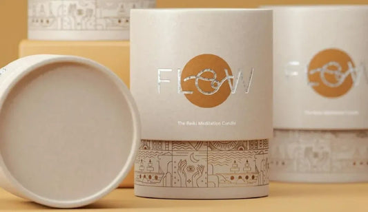 A stylishly designed candle package with metallic lettering and intricate illustrations on the lower part of the container.