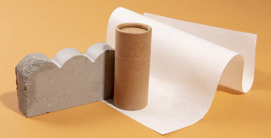 A kraft paper tube next to a paper, set against a yellow background.