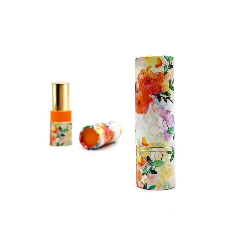 A floral-patterned paper tube with a matching cap, alongside a golden-capped container, on a white background.