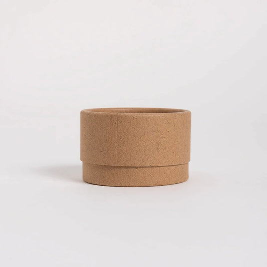 A simple, assembled kraft paper container with a visible seam, shown in profile against a plain white background, embodying a minimalist and sustainable design.