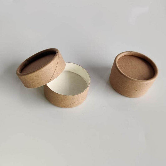 Two open brown paper tubes with one lid askew, revealing a white interior, on a light grey surface.