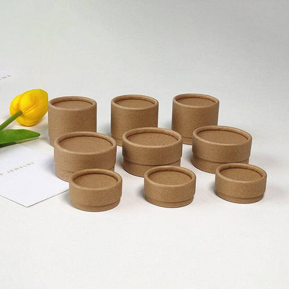 Several open brown paper tubes of varying sizes on a grey surface with a yellow tulip and a white paper in the background.