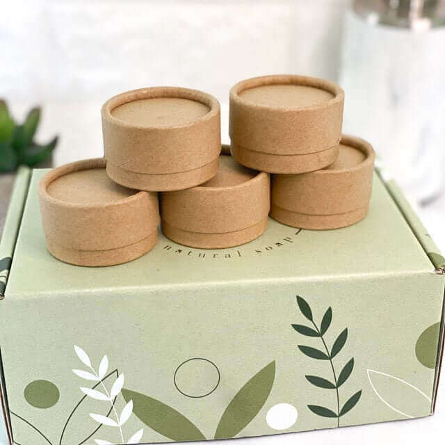 Brown paper tubes arranged atop a decorated box with plant motifs, suggesting eco-friendly packaging.