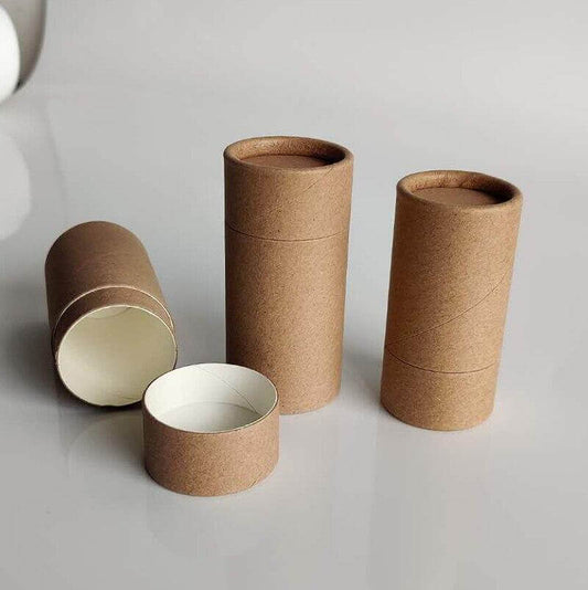 Three upright brown kraft paper tubes and one open horizontally, revealing a white interior, displayed on a reflective surface, embodying a minimalist, eco-friendly packaging design.